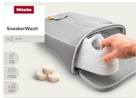 Eine Hand legt einen weißen Sneaker in einen grauen Netz-Waschbeutel, daneben liegen drei Waschmittel-Tabs.